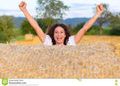 Main thumb excited young woman celebrating farm field standing behind round hay bale laughing cheering her hands raised 75213963